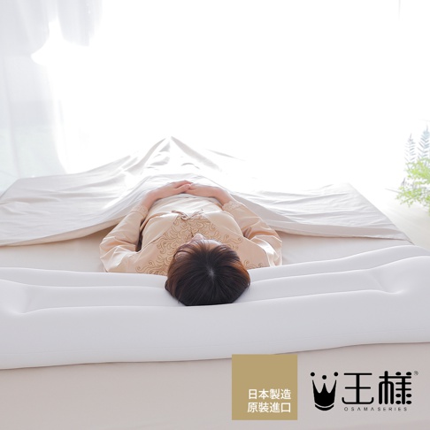 寬長加倍的白色極夢枕，上面躺著一位穿著米色刺繡睡衣的女性，頭部枕在枕頭上，雙手交疊放在胸前，身蓋米白色床單。