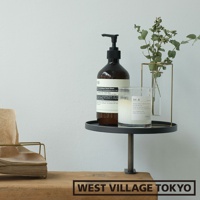 深灰色鐵製圓形可夾式小物桌，桌上擺放著洗手乳、香氛蠟燭及裝飾綠葉，桌腳為金屬材質，整體呈現簡約風格。