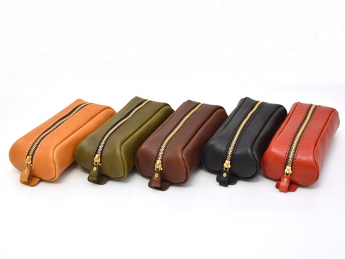 職人手作皮革圓角收納筆袋，展示多種顏色，包括橘色、橄欖綠、深棕色、黑色與紅色。筆袋由皮革製成，帶有金色拉鍊，設計簡潔實用。