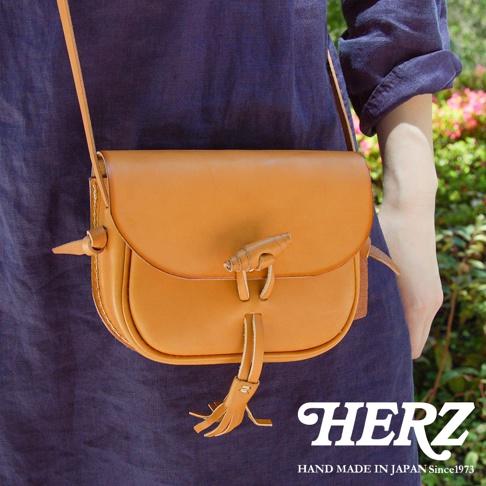 職人手作皮革流蘇側背包，採用天然皮革製作，顏色為溫暖的焦糖棕，包款設計簡約，帶有標誌性的皮革流蘇裝飾，可斜背或側肩背。