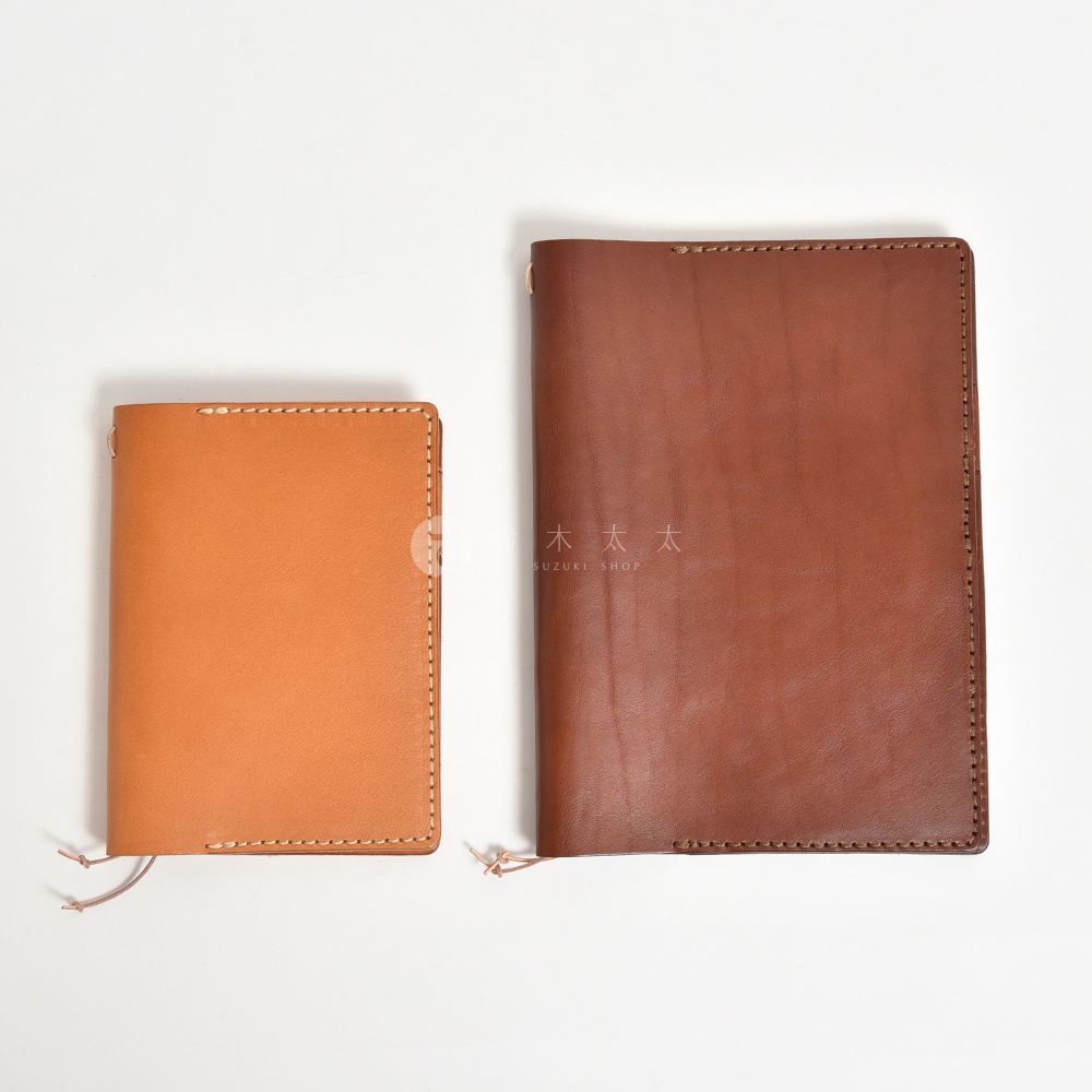 兩個不同尺寸的皮革手帳書套，一個淺棕色，一個深棕色，均以手工縫製，並帶有皮革繫繩。