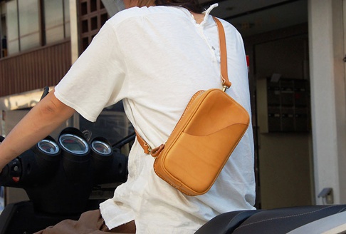 牛皮製成、淺棕色的職人手作皮革兩用直立型斜背包，以斜背方式展示，包身線條流暢，皮革質感自然。