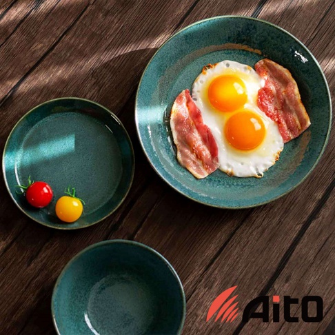 盤子上擺著煎好的太陽蛋和培根，旁邊有兩個小番茄，以及一個空碗和一個空盤，盤子和碗呈現藍綠色，質地類似陶瓷。