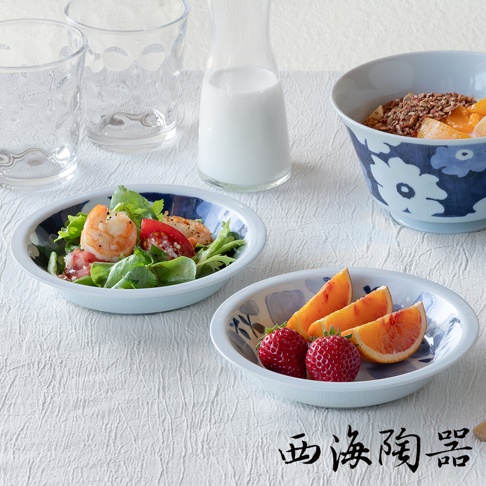 淺藍色陶瓷碟盤，內緣飾有深藍色花紋，盤中盛有沙拉，另有盤子裝有草莓與橘子片。