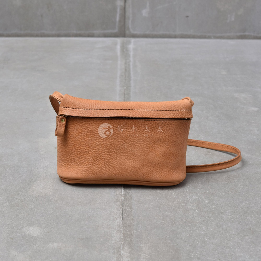 一個棕褐色的皮革斜背包，有拉鍊和細長的背帶。