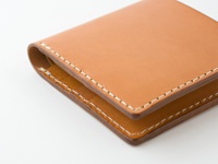 職人手作皮革二折短夾，淺棕色，縫線清晰，材質光滑，簡約設計。