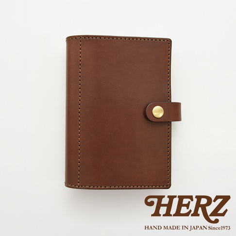 職人手作皮革手帳/記事本書套，深棕色皮革，正面有黃銅按扣，側邊及邊緣以同色系縫線裝飾。