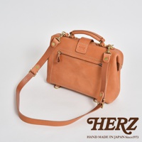 一個棕褐色軟皮迷你杜勒斯包，配有頂部提把、可拆卸肩帶、拉鍊口袋和金色五金件。