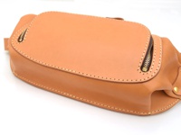 職人手作皮革拉鍊旅行斜背包，呈自然原色皮革，設有兩側拉鍊，縫線精緻，適合日常旅行攜帶。