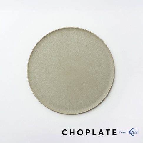 一張從正上方俯瞰的圓形 CHOPLATE 兩用砧板盤，盤面呈現具有細膩紋理的淺灰褐色，邊緣設計簡約。右下方標註有 CHOPLATE 的品牌名稱與 KSJ 的標誌，整體風格極簡現代，展現出其作為廚房砧板與餐桌盛盤的雙重機能感。
