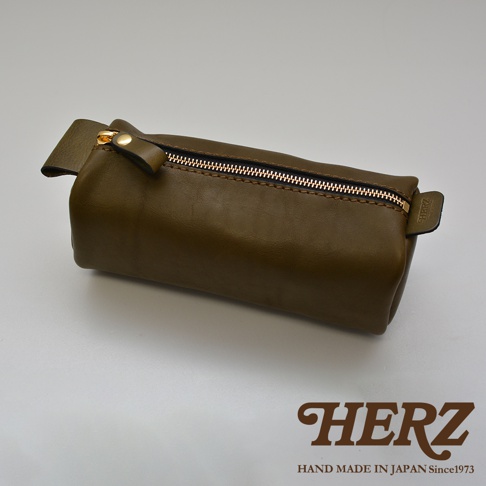 職人手作皮革多用途收納筆袋，橄欖綠色，圓筒造型，頂部有金色拉鍊和皮革拉環，側面有品牌標誌。