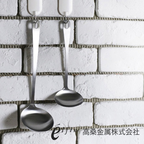 一對日製不鏽鋼湯杓，湯勺部分呈圓弧形，手柄末端有掛孔，湯杓呈現銀白色金屬光澤，掛在白色磚牆上。