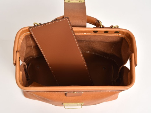 棕色皮革迷你口金包，頂部視角，包身開口，內有隔層，配有金屬鎖扣和手提帶，縫線清晰。