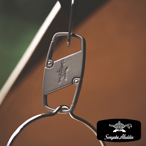 金屬材質的神燈造型掛飾，表面刻有獨特圖騰，搭配登山扣設計，可懸掛於物件上。