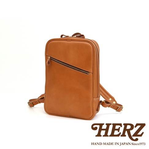 一個長方型的棕色皮革後背包，有拉鍊主袋和一個斜向拉鍊前袋，配有可調式皮革肩帶。