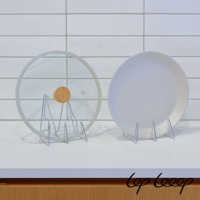 兩個銀色金屬架，左邊架著一個透明玻璃鍋蓋，鍋蓋上有一個木製把手；右邊架著一個白色圓盤。