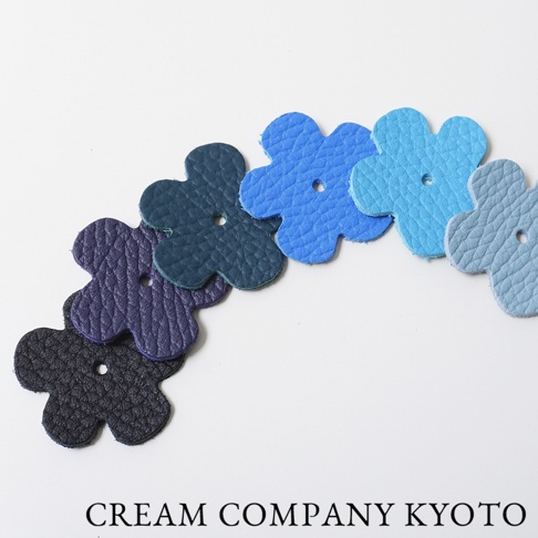 京都職人手作皮革小花吊飾，共展現多種藍色調與深紫色，材質為壓紋皮革，每個小花吊飾中央皆有圓孔。
