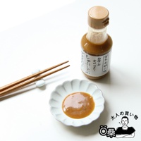 一瓶裝有棕色芝麻醬的玻璃瓶，瓶身貼有日文標籤，旁邊有一個裝有芝麻醬的小白盤和一雙木筷。