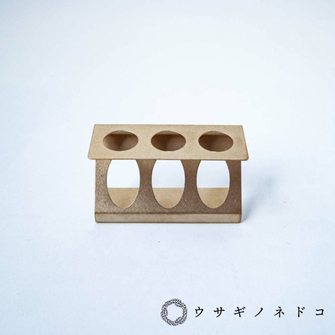 淺棕色紙質試管瓶放置架，有三個圓形孔洞，可容納試管瓶，結構簡潔，放置於白色背景上。