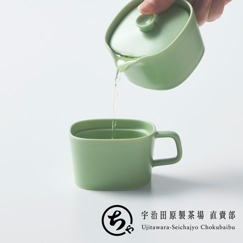 一隻手正將一個淺綠色美濃燒茶壺中的茶湯，緩緩注入下方造型簡約的同色系馬克杯中，底部並標示宇治田原製茶場的品牌標誌。