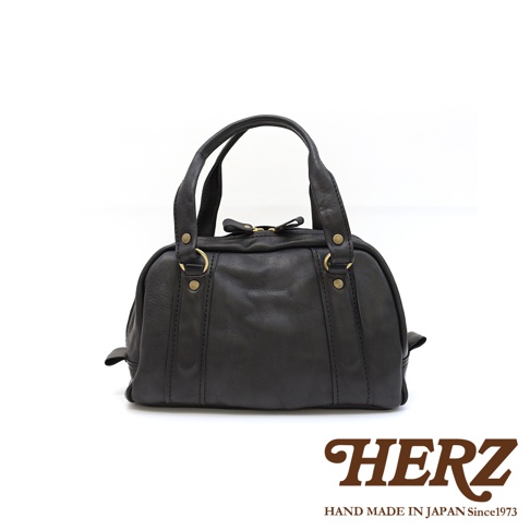 黑色皮革迷你波士頓包，採用水洗加工處理，配有金色金屬拉鍊和兩個提把。包身側面有明顯的皮革縫線裝飾，整體呈現自然隨性的風格。