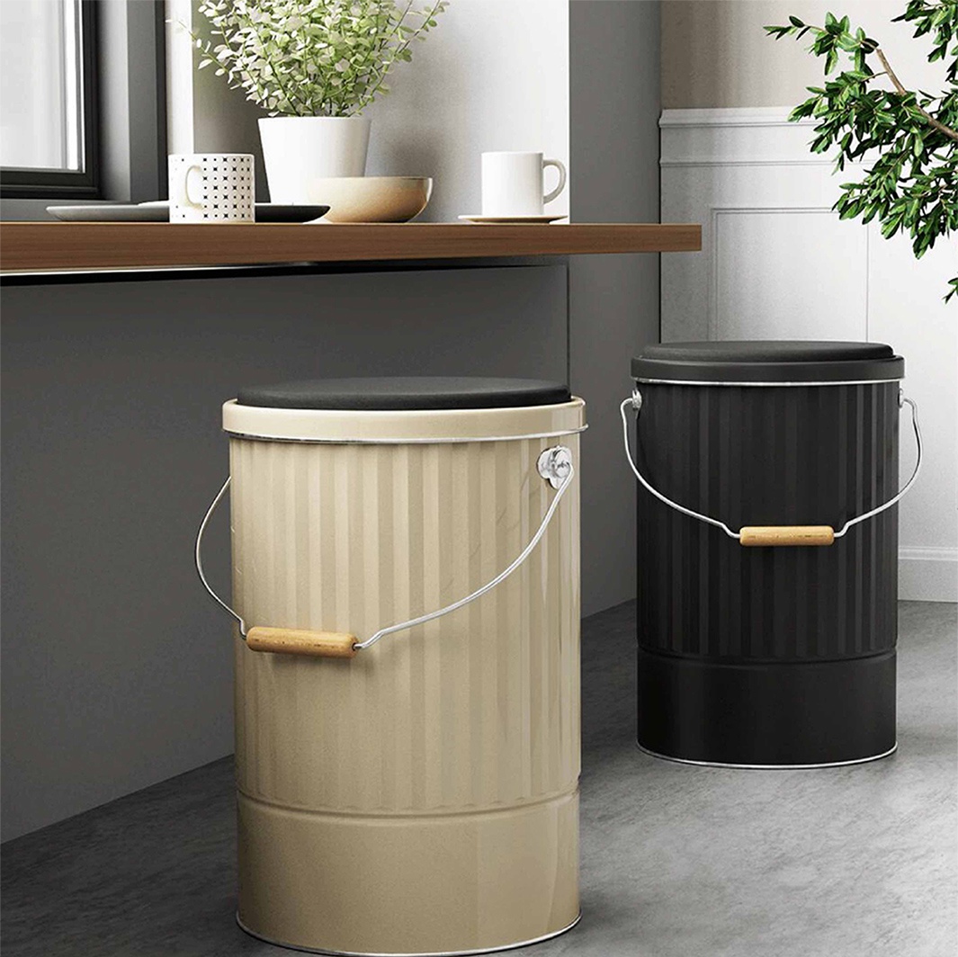 OBAKETSU 手工製凳子儲物桶 L 尺寸，有米色及黑色兩種款式，造型為直條紋金屬桶身，配有木質提把和黑色軟墊座面。