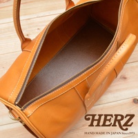 職人手作皮革波士頓包，採用天然棕色皮革，配有黃銅色拉鍊和縫線，展現簡約的設計與精緻的工藝。