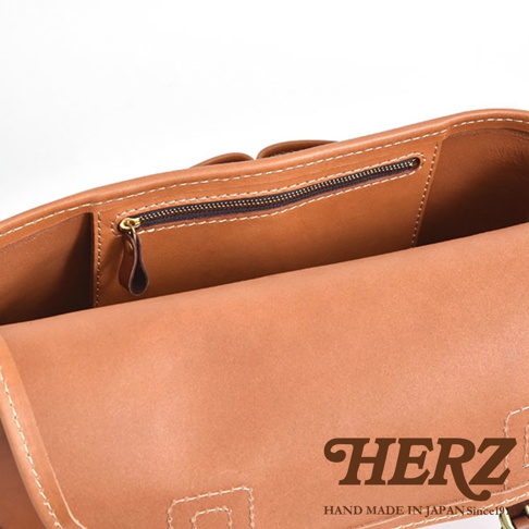 職人手作皮革傳統釣魚包，展示包款內部結構，包含一個拉鍊暗袋和兩個開放式隔層，材質為棕色皮革，縫線清晰。