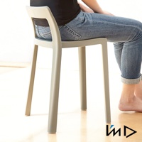 一個淺灰色一體成型塑膠短背椅凳，有四個椅腳，椅背有鏤空設計，一位身穿牛仔褲的人坐於其上。