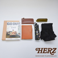 棕色皮革筆記本、咖啡色皮革長夾、橄欖綠皮革筆袋、黑色印花傘、黑色流蘇毛衣。