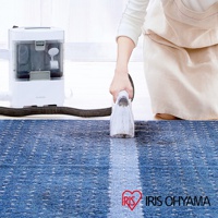 織物清潔機 RNS-300，白色主機連接黑色軟管，由一人手持透明吸頭，清潔藍色條紋地毯。