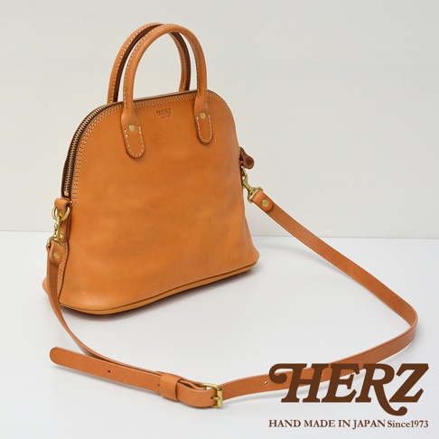 職人手作皮革兩用經典貝殼手提包，天然棕色，光滑皮革材質，圓潤的貝殼造型，雙提把設計，附可拆卸斜背帶，簡約而經典。