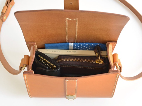 職人手作皮革皮扣單肩包 (CP-38)，打開的淺棕色皮革包內，有鑰匙包、小筆記本、藍色圓點花紋布料，以及側邊的皮革肩帶。