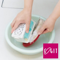 一隻手拿著白色多功能免沾手泡沫洗衣皂盒刷，另一隻手拿著沾有泡沫的帆布鞋，兩者一同置於淺綠色水盆中。皂盒刷為白色塑膠材質，有許多長條形鏤空，內含藍色洗衣皂塊和黃色顆粒。