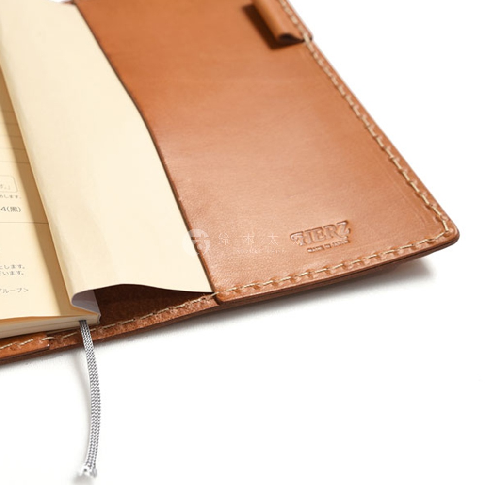 職人手作皮革輕便記事本書套，採用鞣製皮革製成，呈現自然棕色。書套內側有置物夾層，並印有品牌標誌。