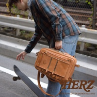 棕色皮革製成的職人手作多功能後背包，具有多個拉鍊口袋和金屬扣環，可手提或肩背。