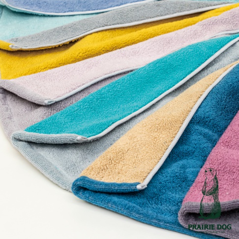 展示多條今治純棉雙股紗半浴巾，顏色包含淺藍、灰色、黃色、淺紫、藍綠色、卡其色、深藍色及粉紅色，毛巾邊緣有滾邊設計。