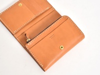 職人手作皮革中型雙折短夾，採用原色皮革製作，設有拉鍊零錢袋、多個卡槽及鈔票夾層，以白色縫線手工車縫，質感細膩，品牌標誌印於內側。