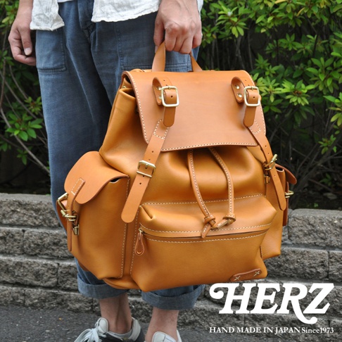 職人手作皮革復古風旅行後背包，經典棕色，採用光滑皮革材質，配有側袋、束繩開口、雙搭扣翻蓋及可調式肩帶，整體風格復古耐用。