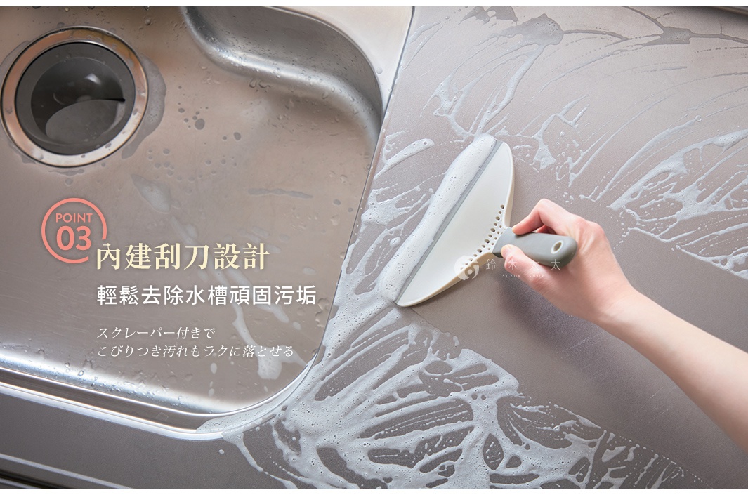 一隻手握著白色的多功能清潔刮鏟，正在清潔帶有泡沫的廚房流理台，刮鏟邊緣貼合檯面，呈現出俐落的清潔動作，畫面左側標示著點三內建刮刀設計，強調能輕鬆去除水槽頑固污垢，整體呈現明亮且實用的居家清潔場景。