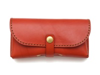 橘紅色皮革手作眼鏡收納盒，附有金屬釦帶及縫線裝飾，設計簡潔，材質為皮革。