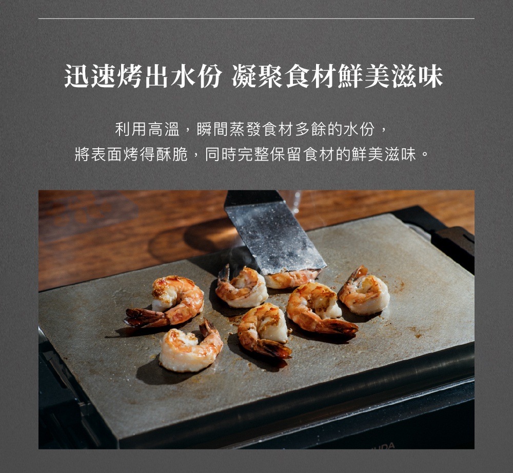 黑色極致電烤盤上烤著七隻鮮紅色的蝦子，其中一隻蝦子被銀色金屬鏟子翻動。
