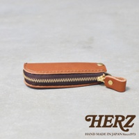 職人手作皮革Organ拉鍊鑰匙包，展示了焦糖色皮革，配有黃銅拉鍊和鉚釘，整體呈圓潤的長方形。