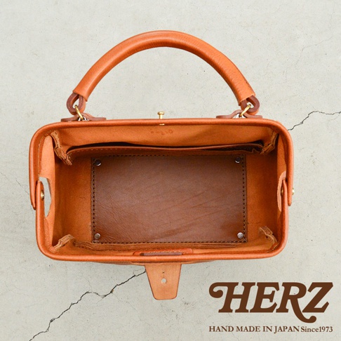 職人手作皮革Organ兩用方形口金托特包，材質為天然皮革，呈現溫潤的棕褐色，包款上方有提把，內部結構清晰可見，擁有隔層設計，整體風格簡約而質感。