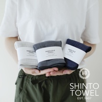 三條 INNER PILE 雙面紗布輕質浴巾，分別為淺灰色、炭灰色與海軍藍，均以白色標籤包裝，標籤上印有產品名稱與製造資訊。