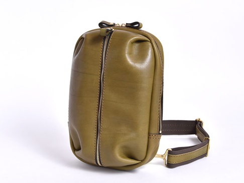橄欖綠皮革立體運動斜背包，側面有拉鍊，搭配可調節的深棕色織帶和金色金屬扣環。