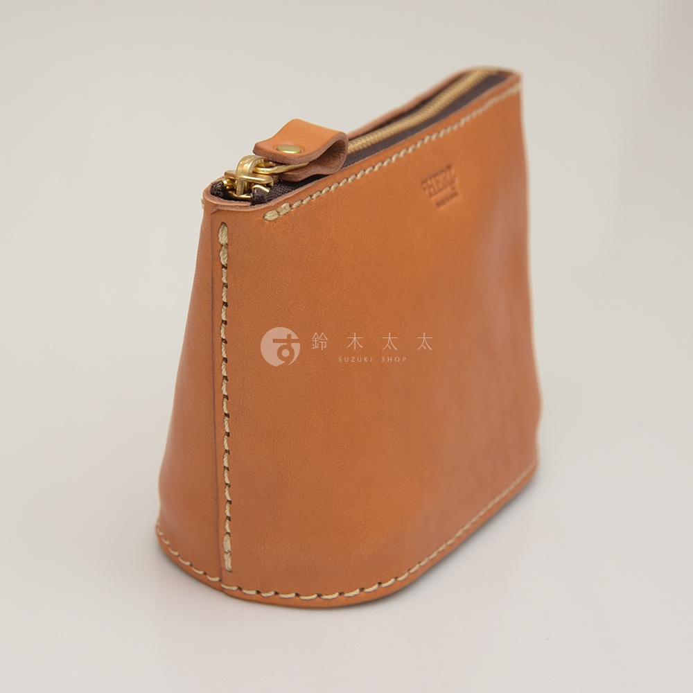 職人手作皮革三角收納包，淺棕色皮革，圓潤底部，頂部有金色拉鍊與皮革拉環，側邊與底部縫線明顯。