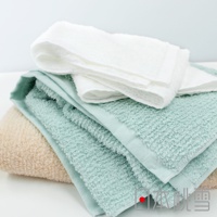 一疊今治細絨浴巾，包含米色、淺綠色和白色，材質柔軟，觸感細緻。