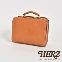 職人手作的棕色皮革方形單肩包，帶有頂部提把和可拆卸肩帶，縫線清晰，金屬配件。