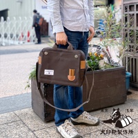 深棕色純棉帆布三用橫式側背包，配有棕色皮革飾邊和手提把，以及可拆卸的肩帶，包包上有品牌標誌貼布。